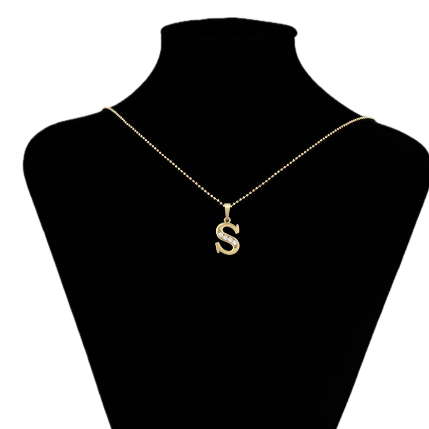 Gold necklace with a 'S' pendant on a black mannequin bust.